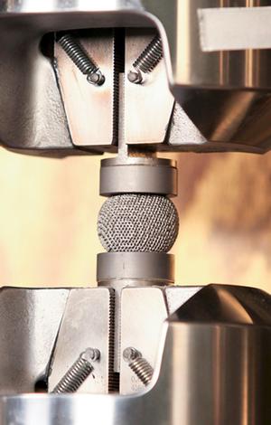 A titanium mesh sphere is positioned in an ORNL lab to be crushed-destructive testing to obtain parameters for DARPA's $50,000 DMACE Challenge.