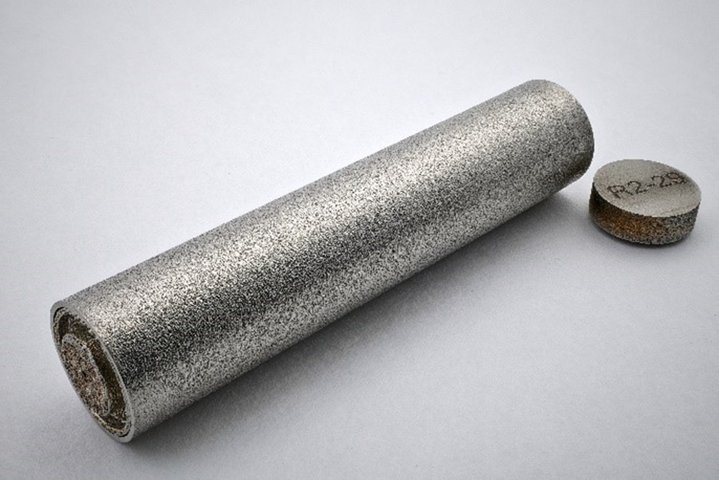 Singular stainless steel capsule laying flat with a close up of the cap that reads "R2-29"