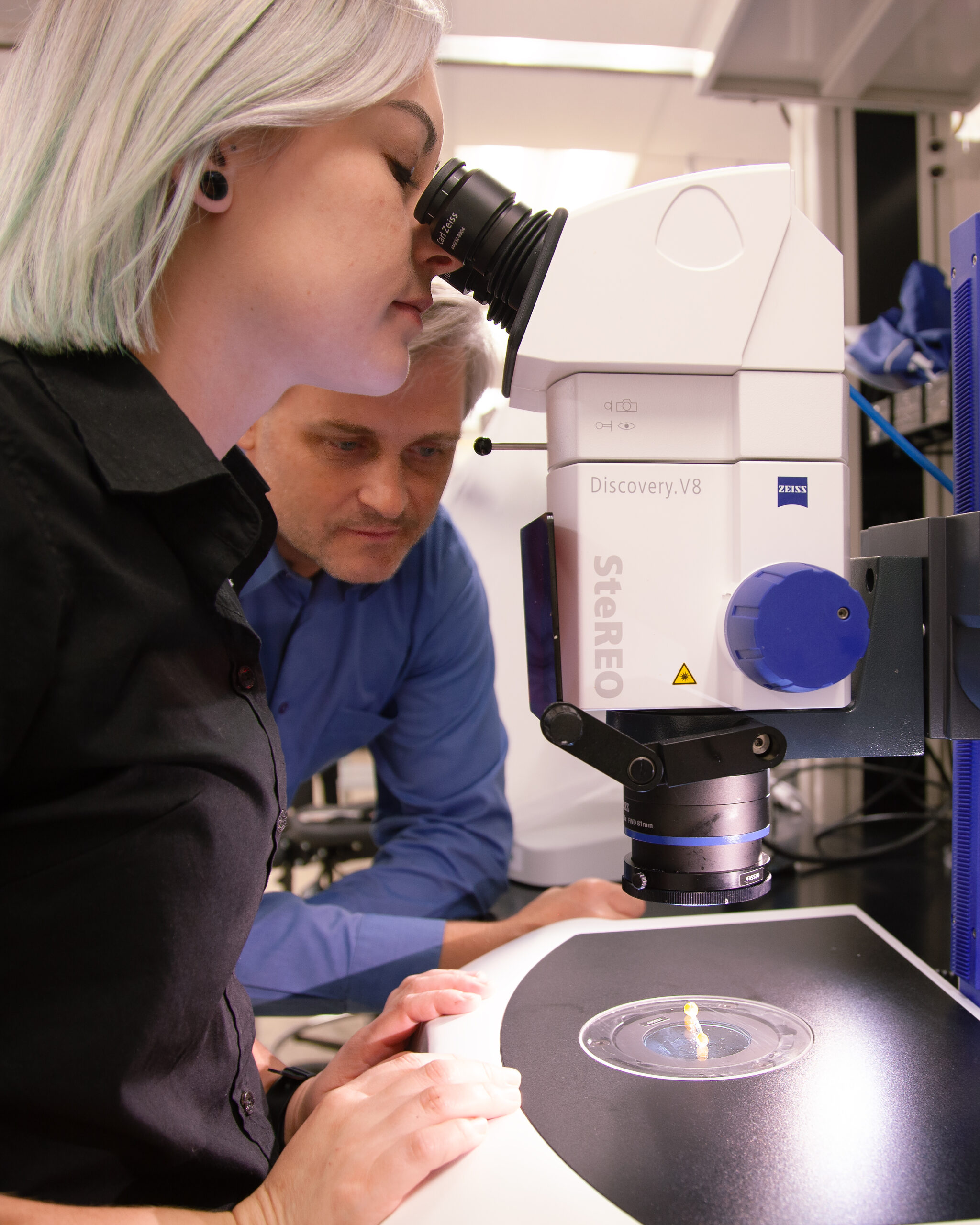 Victoria looking into a microscope and Andrii beside her looking at the crystal sample.