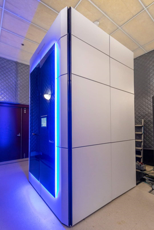 A phone-booth sized white enclosure emitting a blue glow