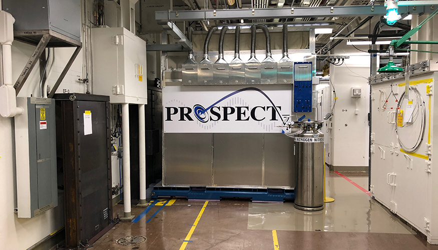 The PROSPECT neutrino detector in a lab at Oak Ridge National Laboratory, with pipes overhead and a nitrogen tank nearby.