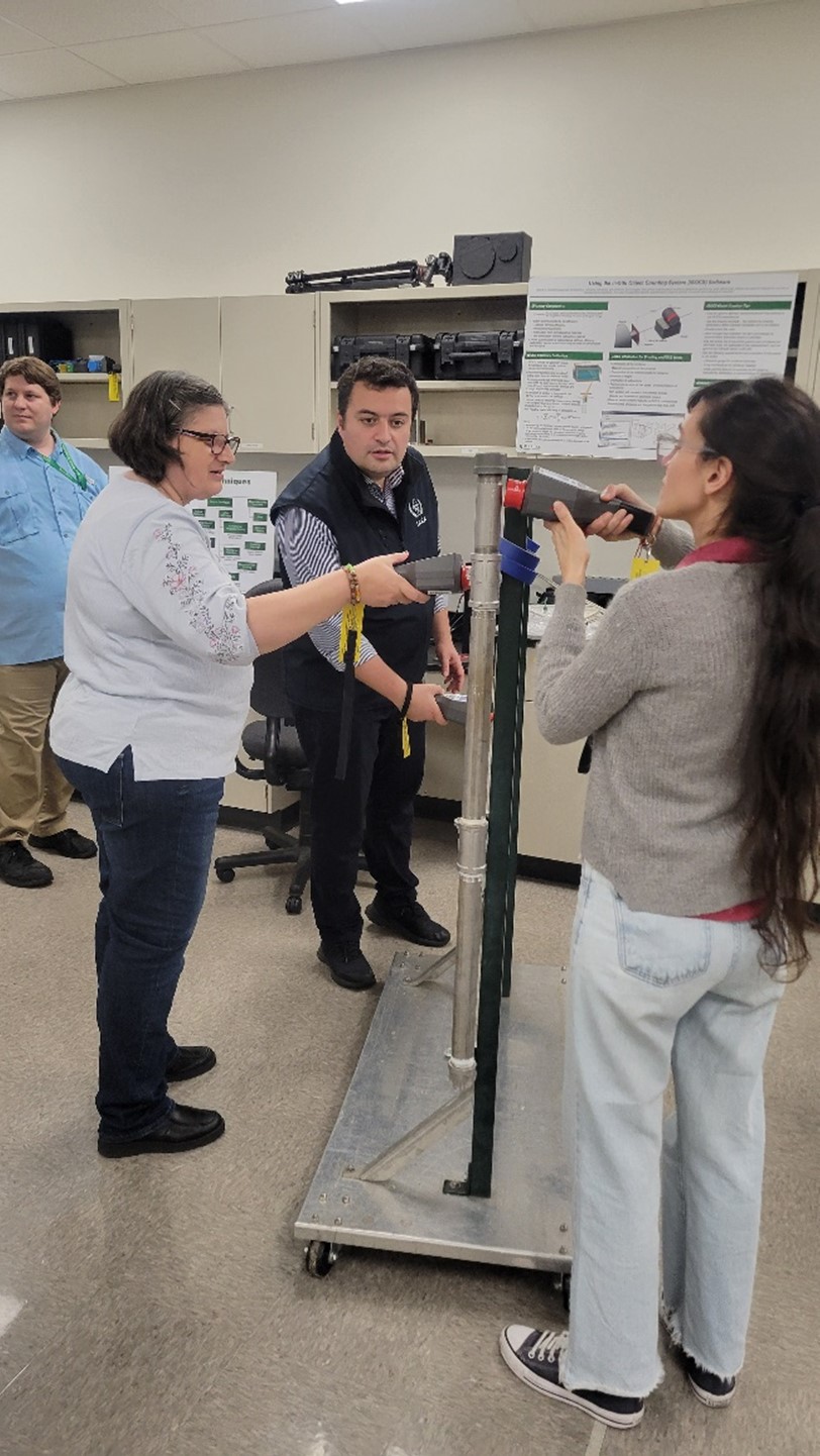 Three participants of the workshop look at safeguard technology on black and metal vertical poles