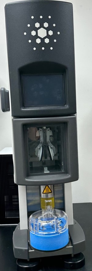a tall black cylinder with a funnel and blue bucket at the base