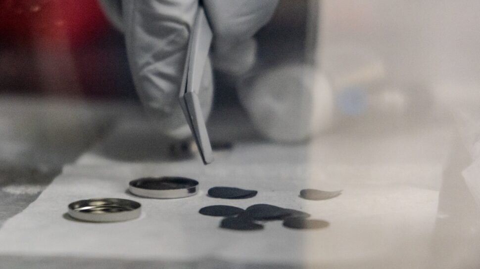 A researcher holds a lightweight current collector developed at the Battery Manufacturing Laboratory using aligned carbon fibers with very thin polymer layers.