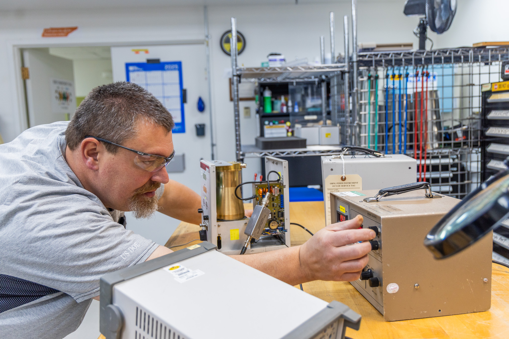 echnician calibrating electronic test equipment in a laboratory workspace.