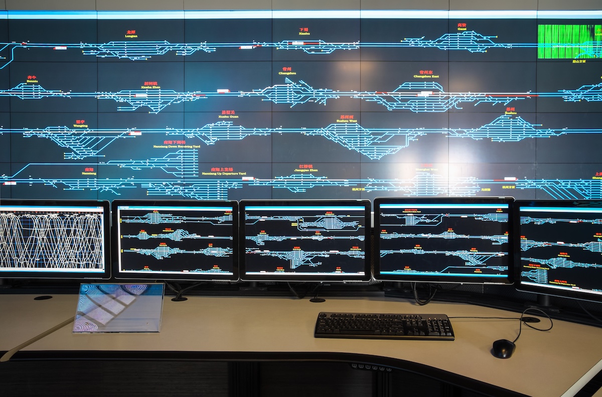 A photograph showcases a high-tech control room featuring numerous display panels and computer monitors. Image from Envato