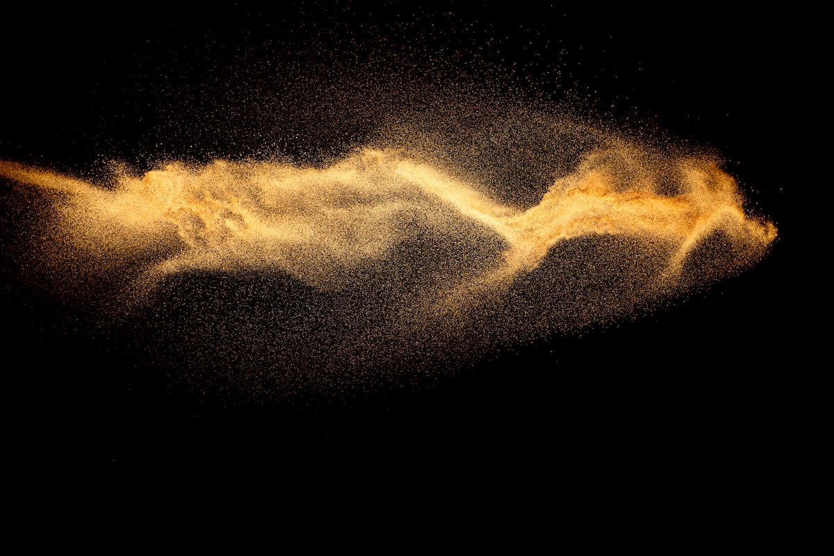 Brown color sand splash against black background. Image from Envato