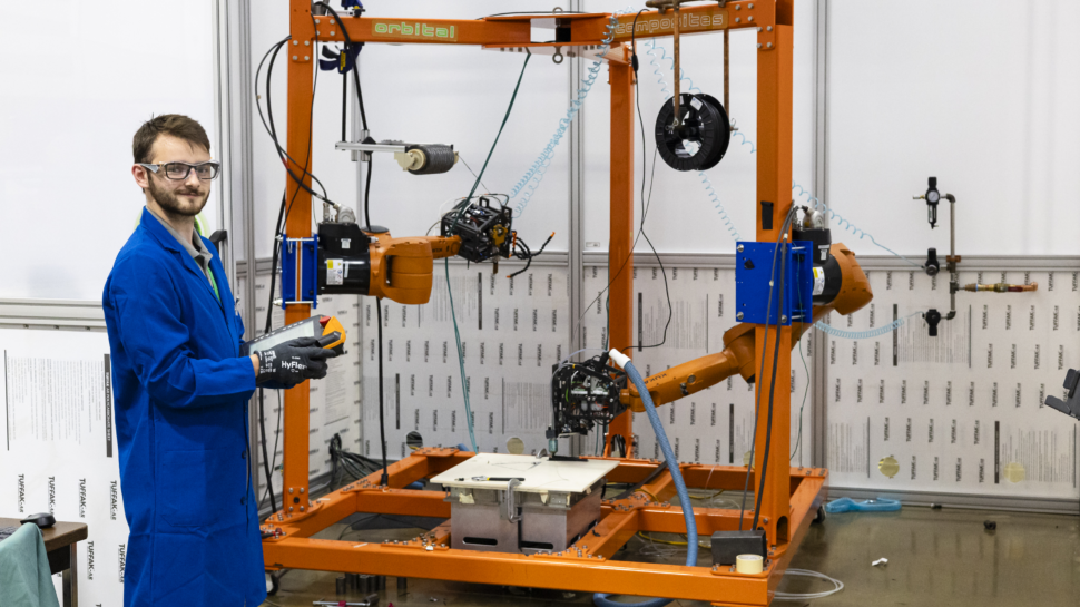 A student wearing safety glasses and a lab coat working with equipment at the MDF, Manufacturing Demonstration Facility.