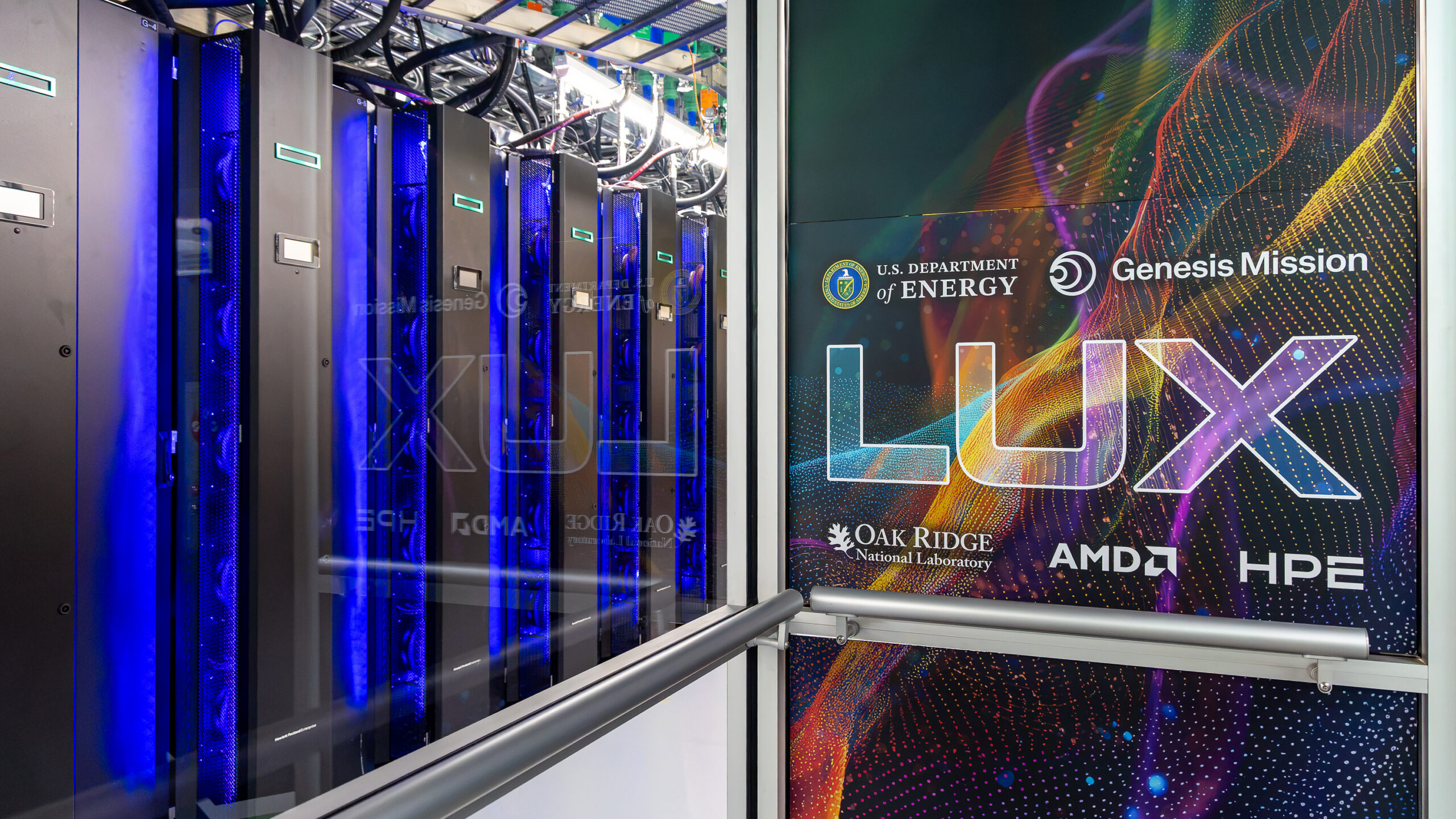Rows of black computing cabinets with blue-lit cooling fans fill an ORNL data center as personnel conduct a safety walkthrough of the Discovery and LUX systems.