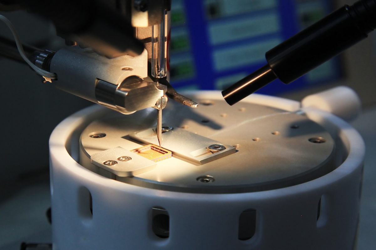 This close-up shot features a complex semiconductor chip being analyzed under a microscope or other high-precision testing equipment. Image from Envato