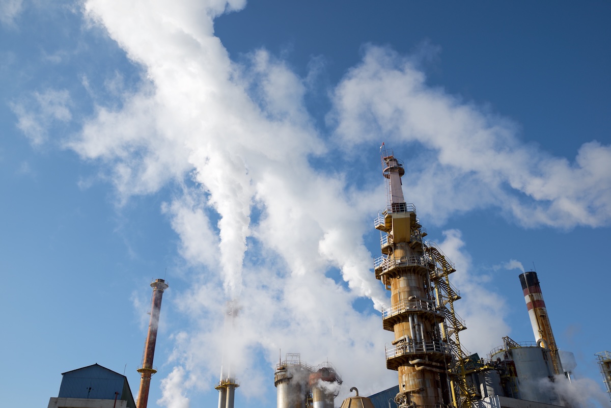 Low angle shot of smokestacks in a paper mill in Spain. Image from Envato