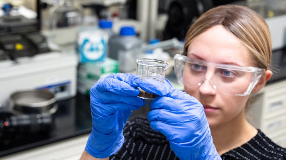 Greta Franke holds a soil sample while posing in a laboratory in Room 307 of Building 1505 at Oak Ridge National Laboratory.