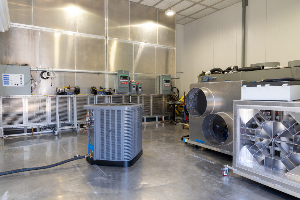 A laboratory space with HVAC equipment, ductwork and testing systems arranged on a polished floor.