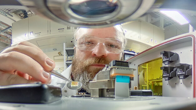 A scientist's face partially obscured by an experiment