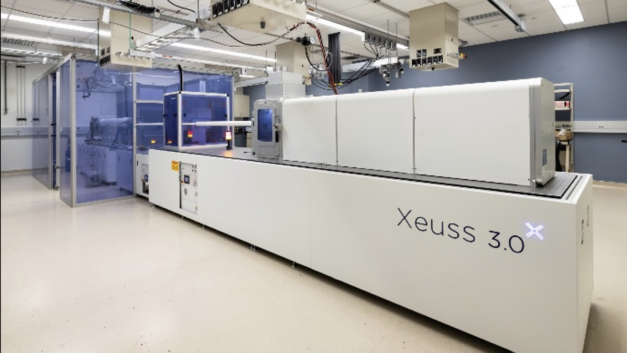 A long white counter-size enclosed machine opening into a blue-walled workspace