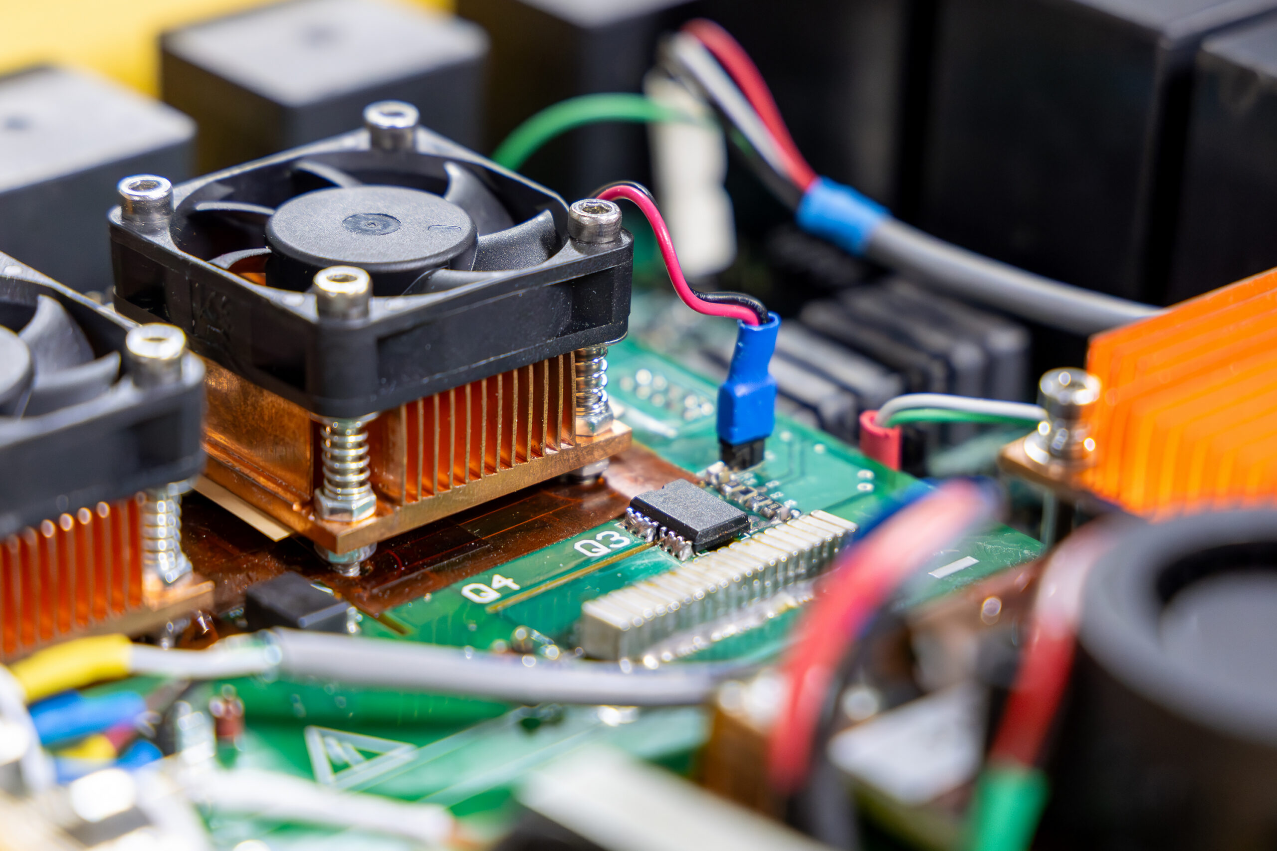 A compact electronic power converter with cooling fans and heat sinks inside a yellow casing, photographed in a studio setup.