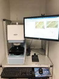 An encased microscope next to a monitor