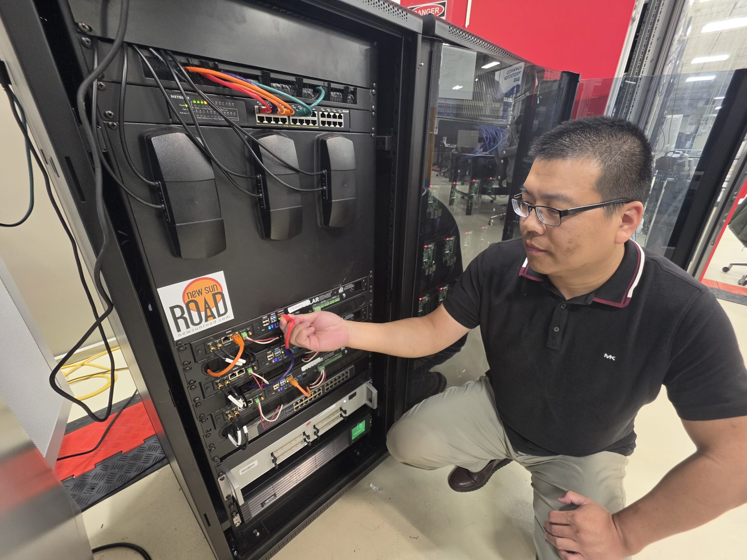 Researcher inspects connections in a computer equipment rack.