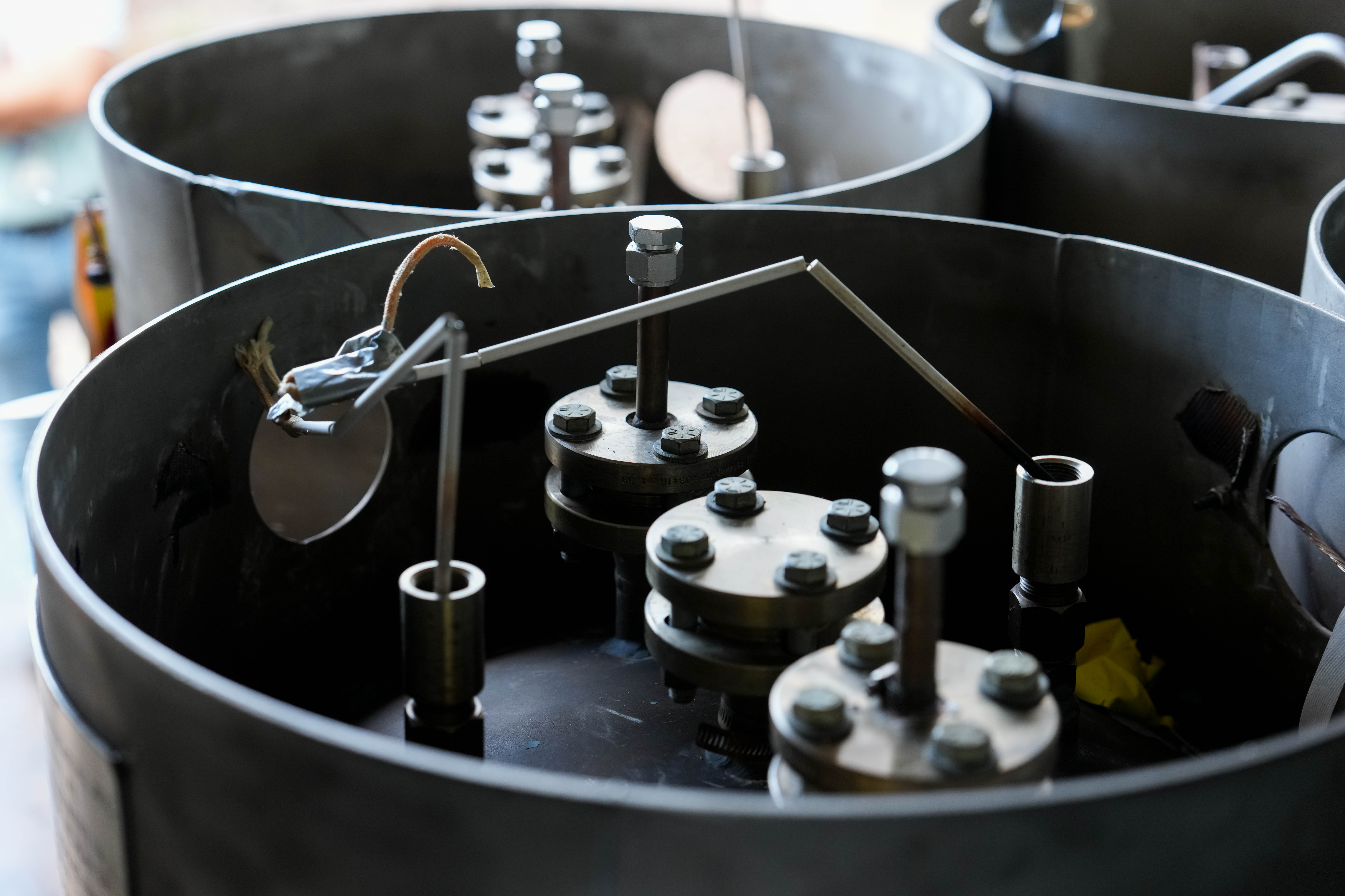 Close-up of metal components and tubing inside a cylindrical apparatus.