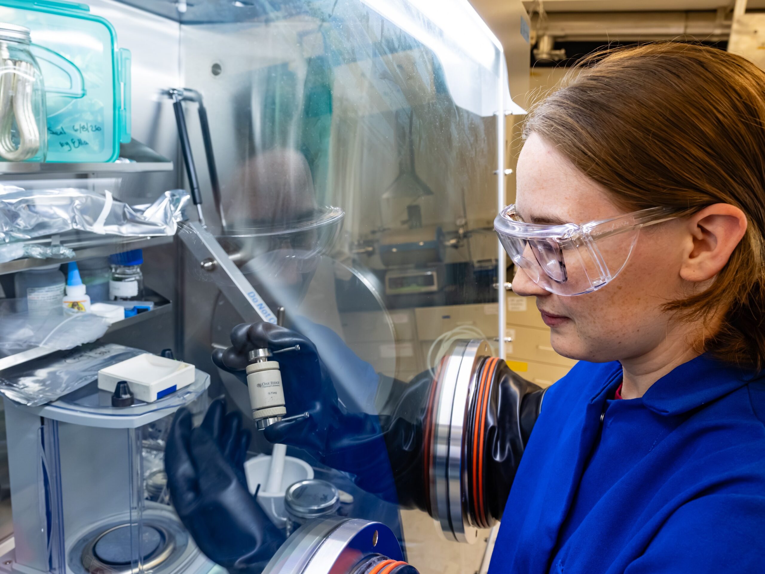 ORNL researcher works with materials inside a laboratory glovebox.