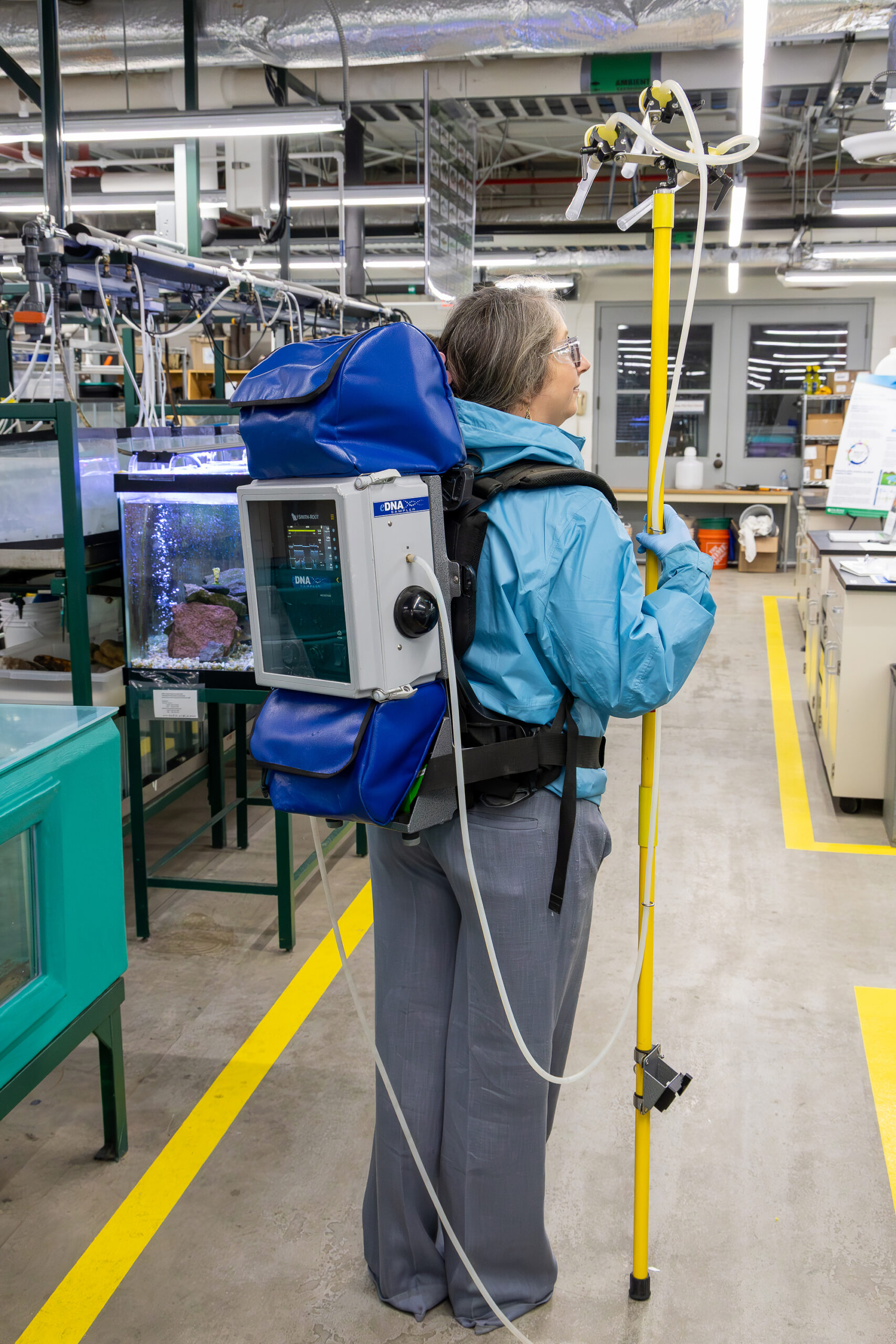 A researcher wears a backpack-style environmental DNA sampler.